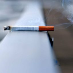 A lit cigarette sitting on a ledge.