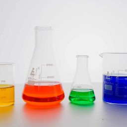Different colored liquid chemicals in beakers.