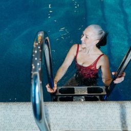 Woman using a ladder to get into the pool.