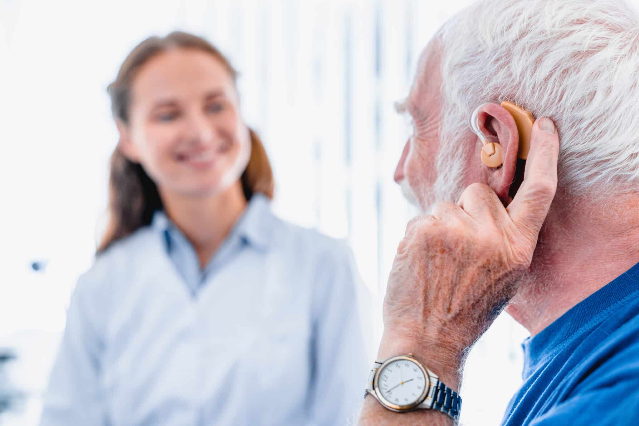 senior-man-hearing-loss-hearing-aid Older man with a hearing aid speaking to his audiologist/