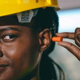 Female construction worker putting an earplug into her ear.