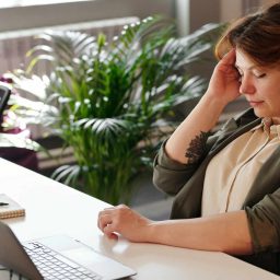 Woman experiencing a migraine at work.