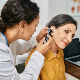 Woman receiving an ear exam to check for hearing loss.