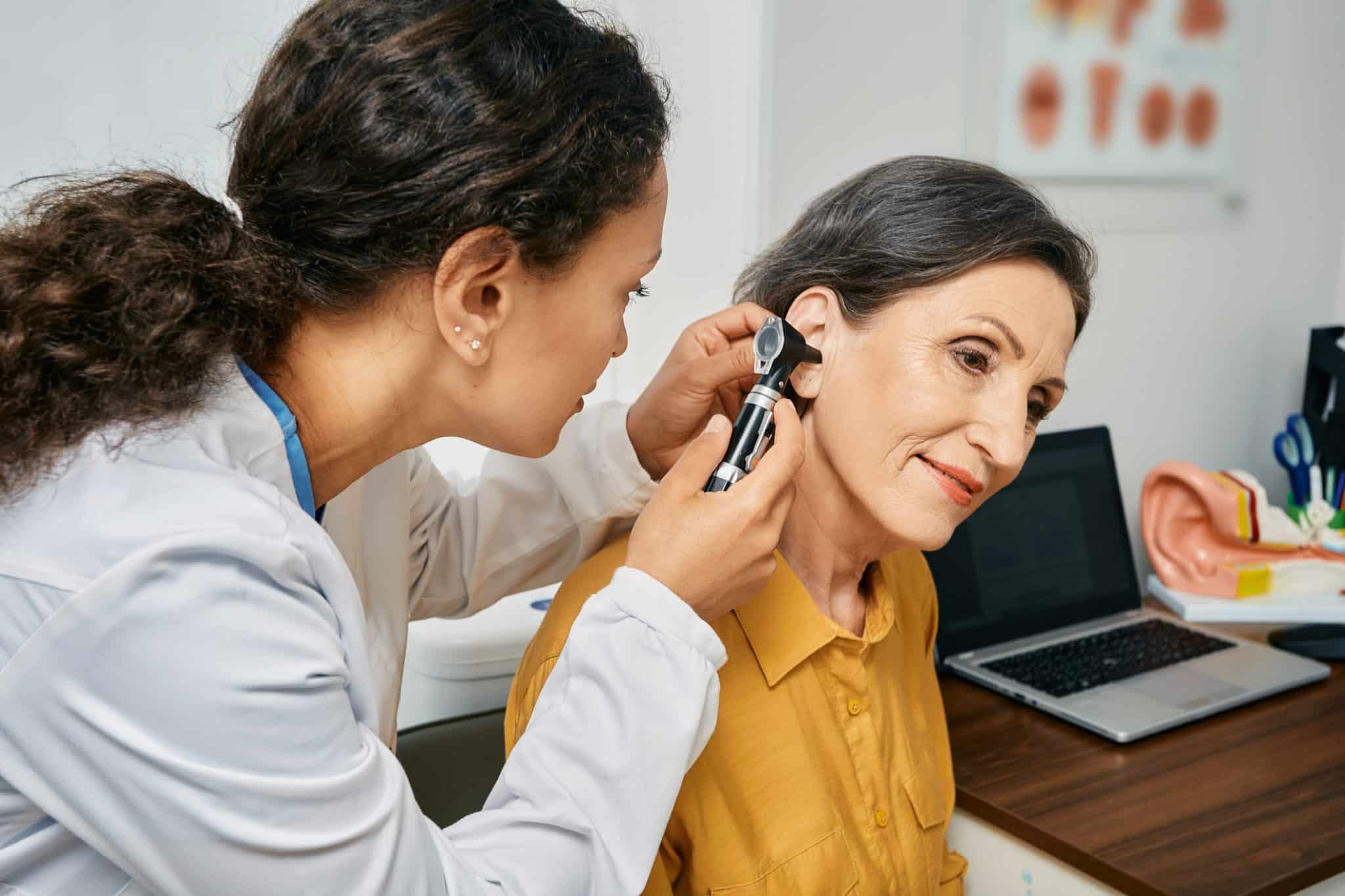 Woman receiving an ear exam to check for hearing loss.