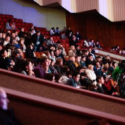 Group of people watching a performance in an auditorium.