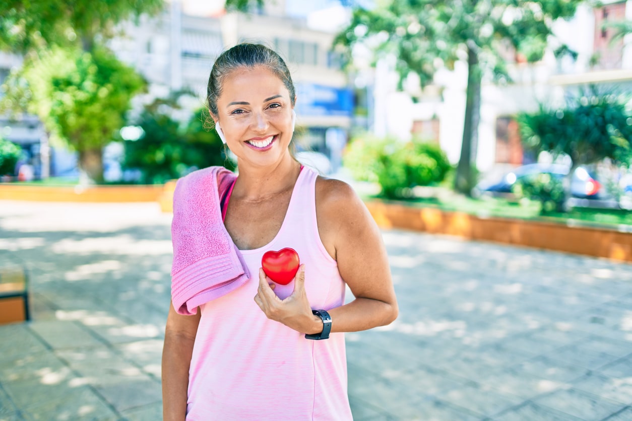 Woman on a run holding a heart up to her chest.