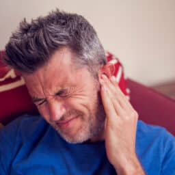 Man with tinnitus holding his ear