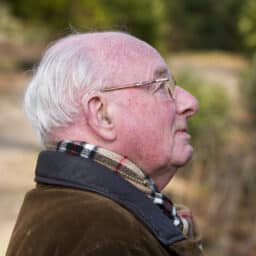 Senior man wearing his hearing aid in the chilly weather