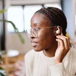Woman touches hearing aid behind ear