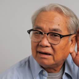 Man holds hand behind ear