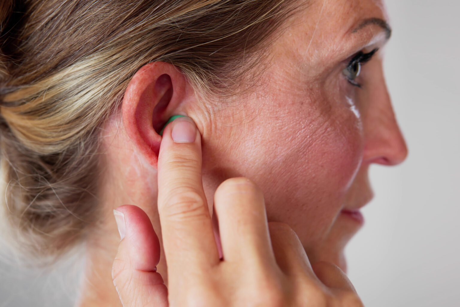 Woman inserting an earplug to protect her hearing.