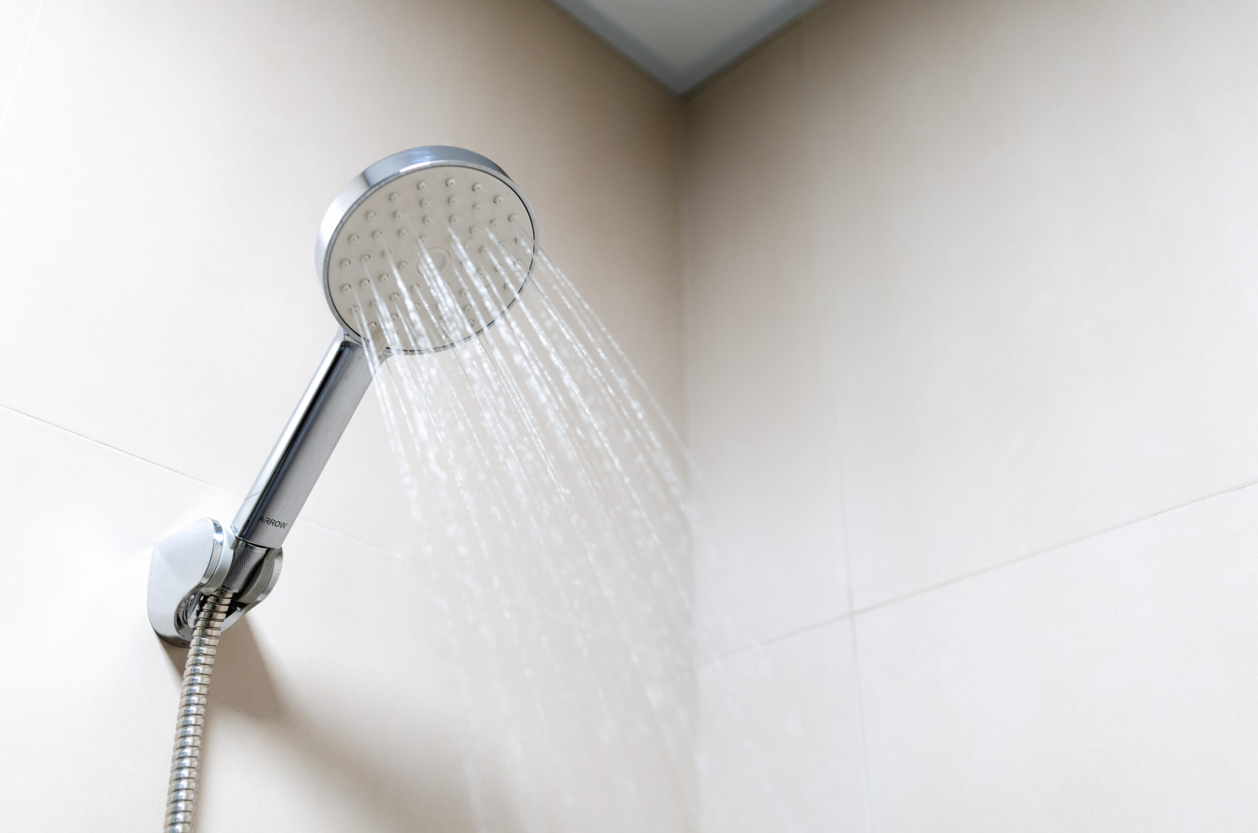 A shower head with the water turned on. Walking into the shower with your hearing aids in can cause water damage.