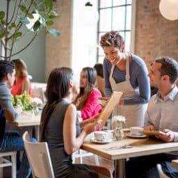 Couple dining in a crowded, noisy restaurant with a friendly server