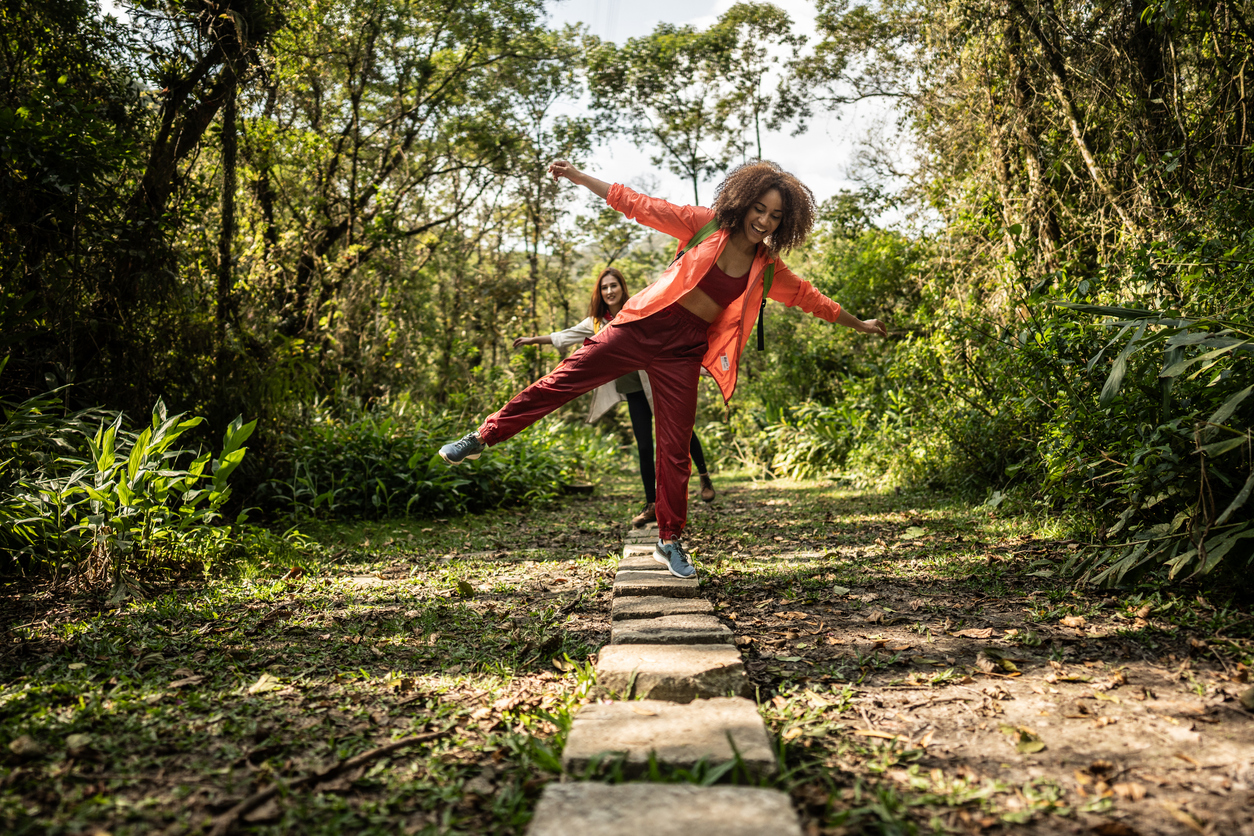 Woman in the forest balancing on a rock wall.